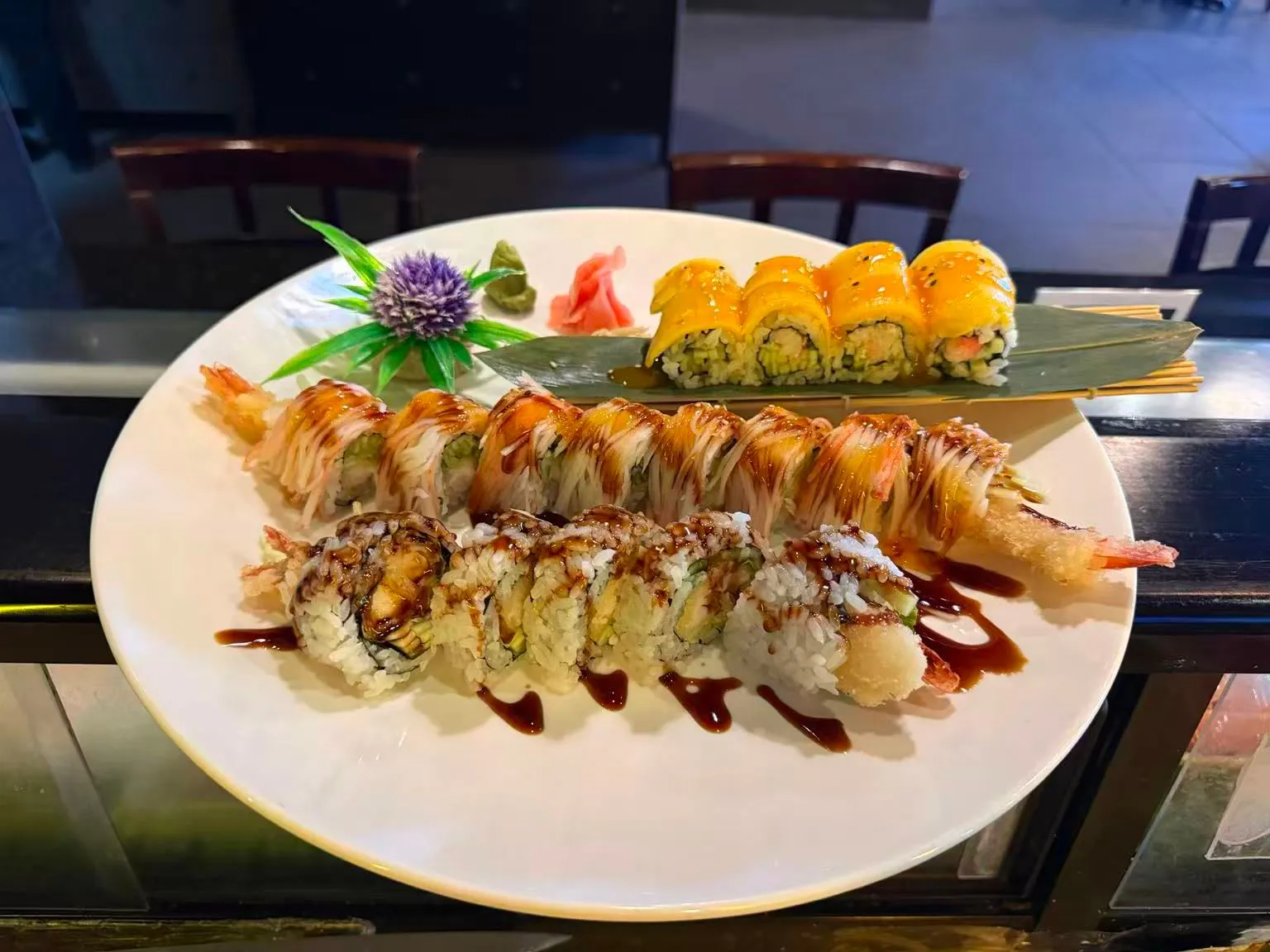 Assorted gourmet sushi rolls with tempura shrimp, mango topping and savory sauce