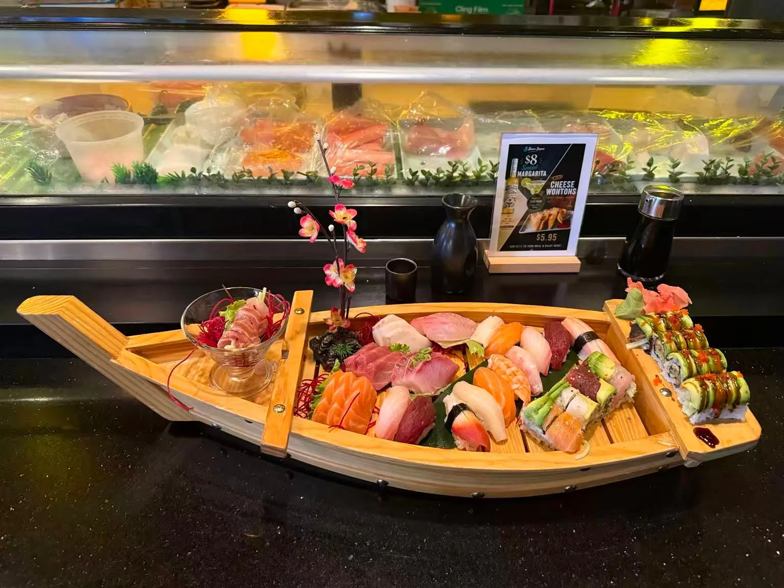 Wooden sushi boat platter with sashimi, nigiri, sushi rolls and garnishes
