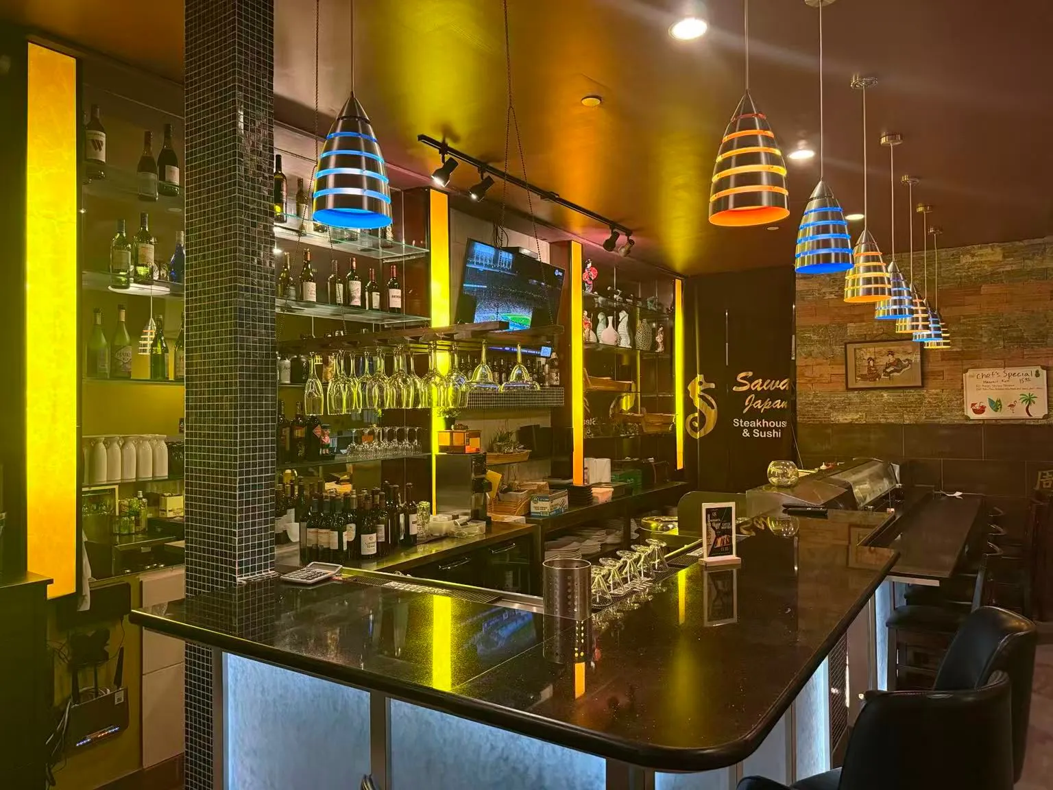 Stylish restaurant bar with wine bottles, colorful pendant lights and Sawa Japan branding