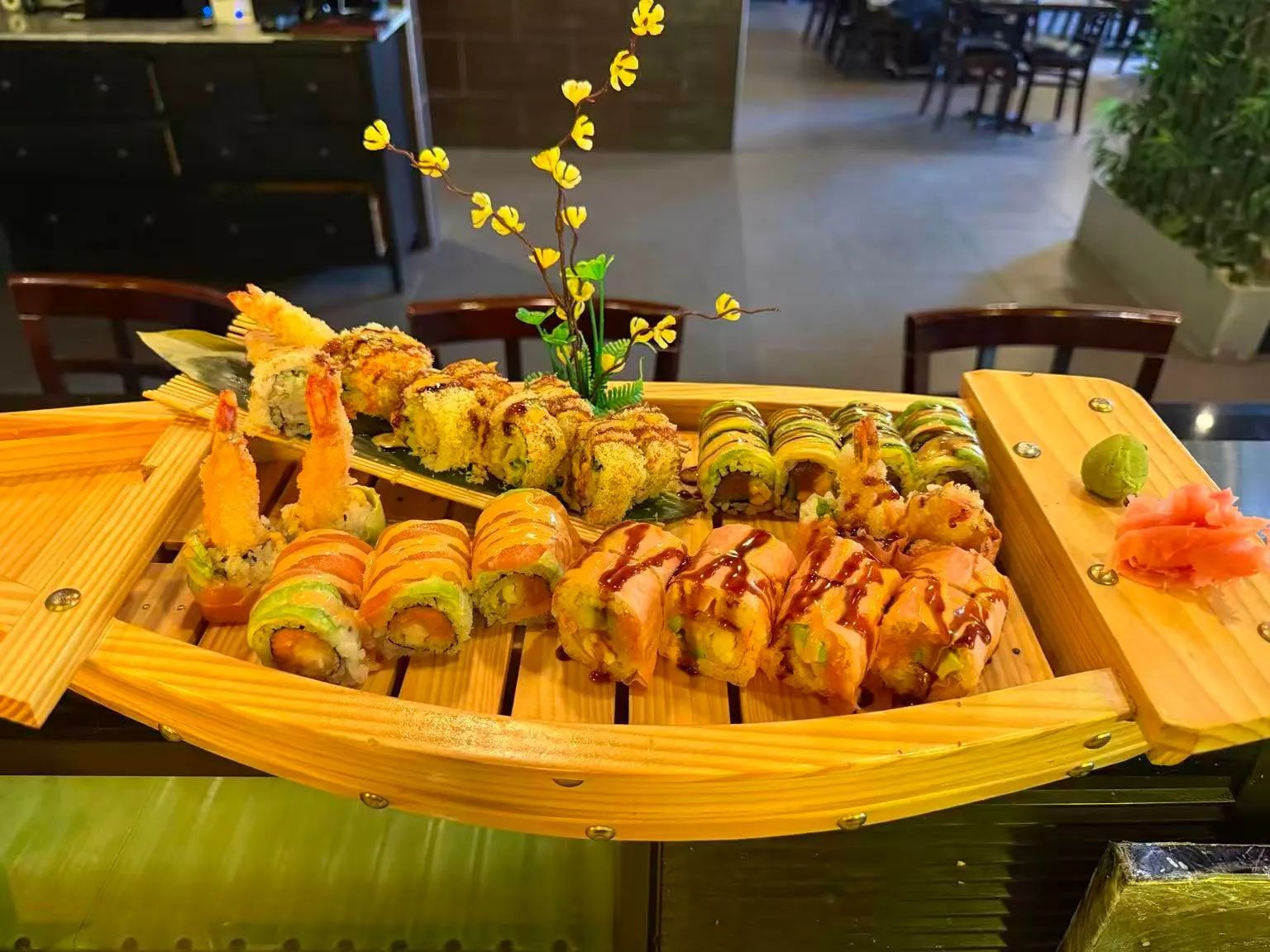 Large wooden sushi boat filled with various specialty sushi rolls and tempura shrimp